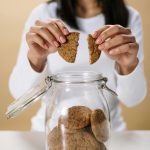 Woman breaks a cookie in half, illustrating the changes in cookie and privacy rules.